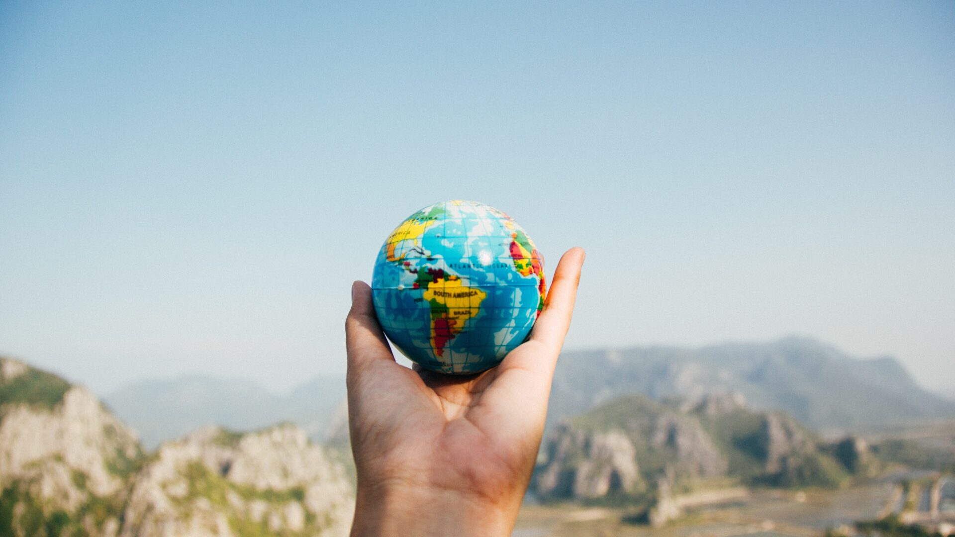 Stock image showing a hand holding a miniature globe