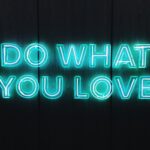 A blue neon sign spelling out "do what you love" in all caps.
