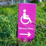 A stock image representing the accessibility them. The photo shows a sign with a wheelchair icon and "Step free Route" written under it. The sign is placed on grass