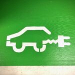 A simple sketch of the outline of a hybrid car, white against green background.